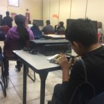A student examines a motherboard in the back of class.