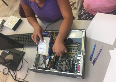 After a short lesson on hardware components and operating systems, students take turns disassembling and reassembling a desktop.