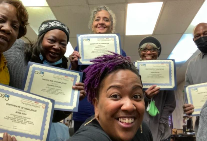 Instructor poses in a selfie with five adult students holding their certificates