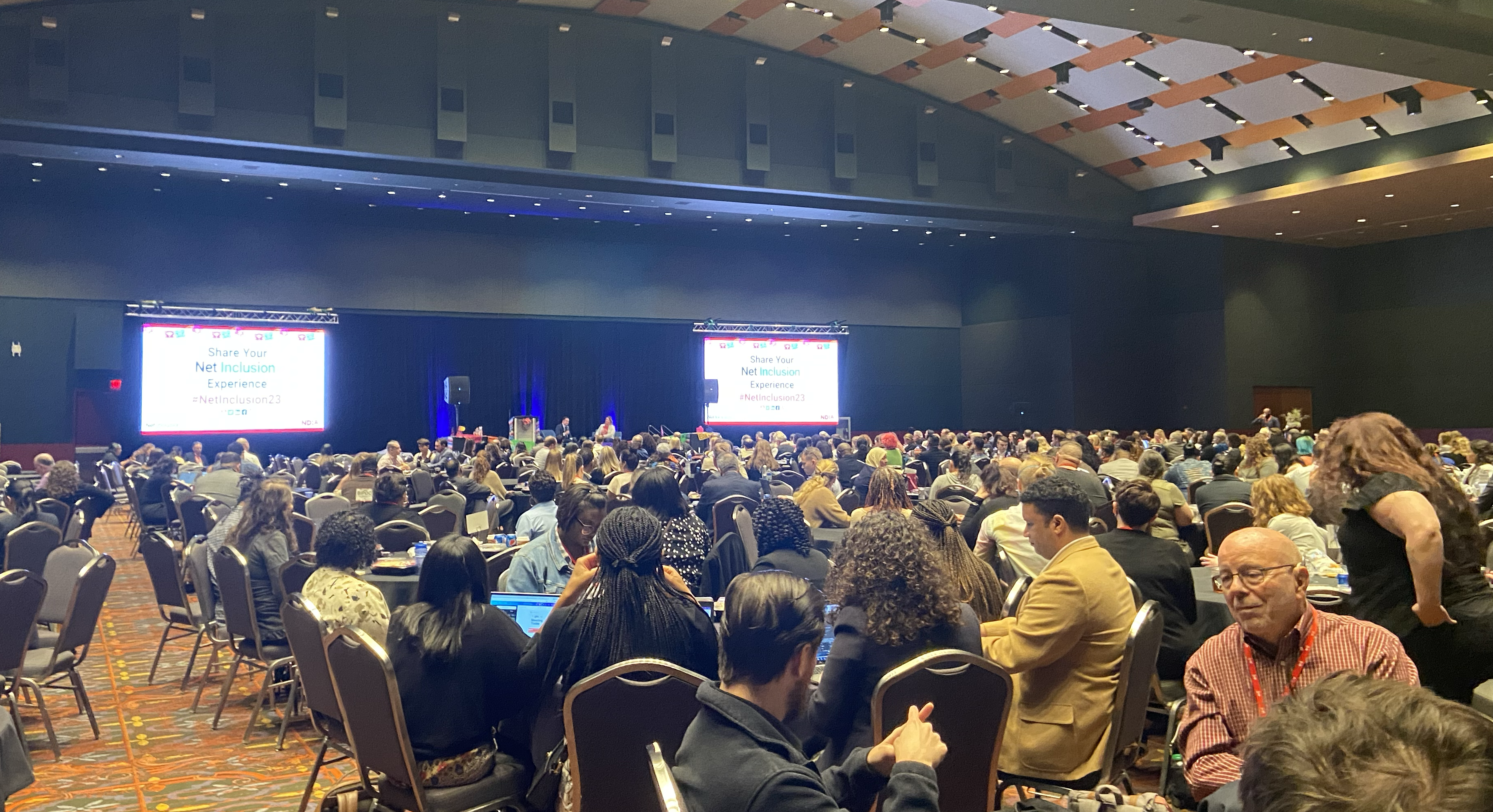 View from the back of a crowded conference ballroom with 800 people. Two people are on stage