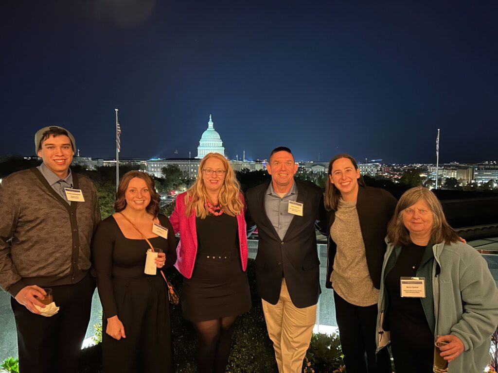 6 Digital Navigators and NDIA Staff members posing in front of the Capitol at night