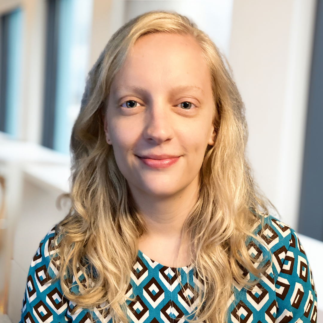 Headshot of a white woman with blond hair and a blue patterned top