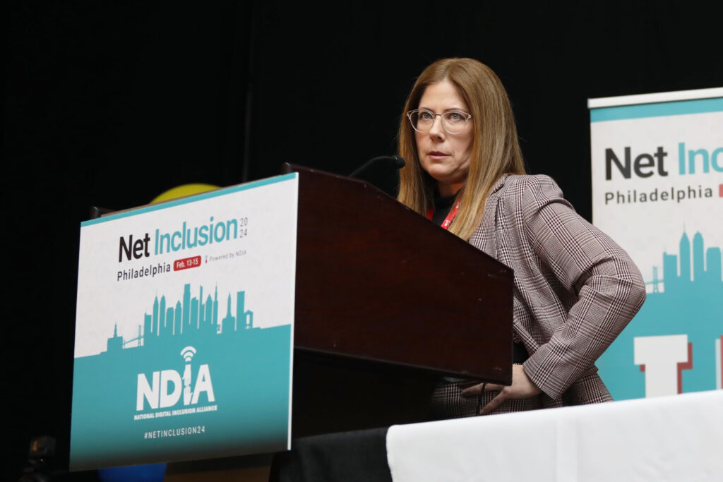 Woman stands with her hand on her hip and Net Inclusion sign